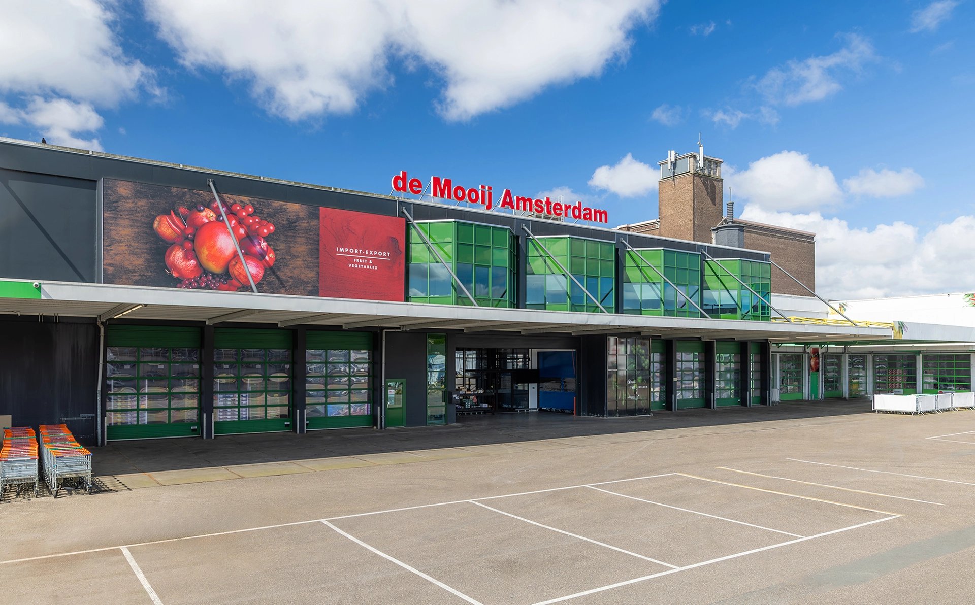 Gevel van de Mooij Amsterdam met rood logo en fruitreclame boven de laaddokken