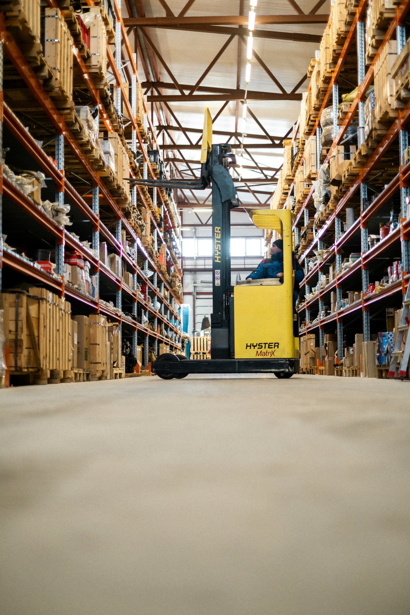 Reachtruck-heftruck in het middenpad van het magazijn, tussen pallets en artikelen