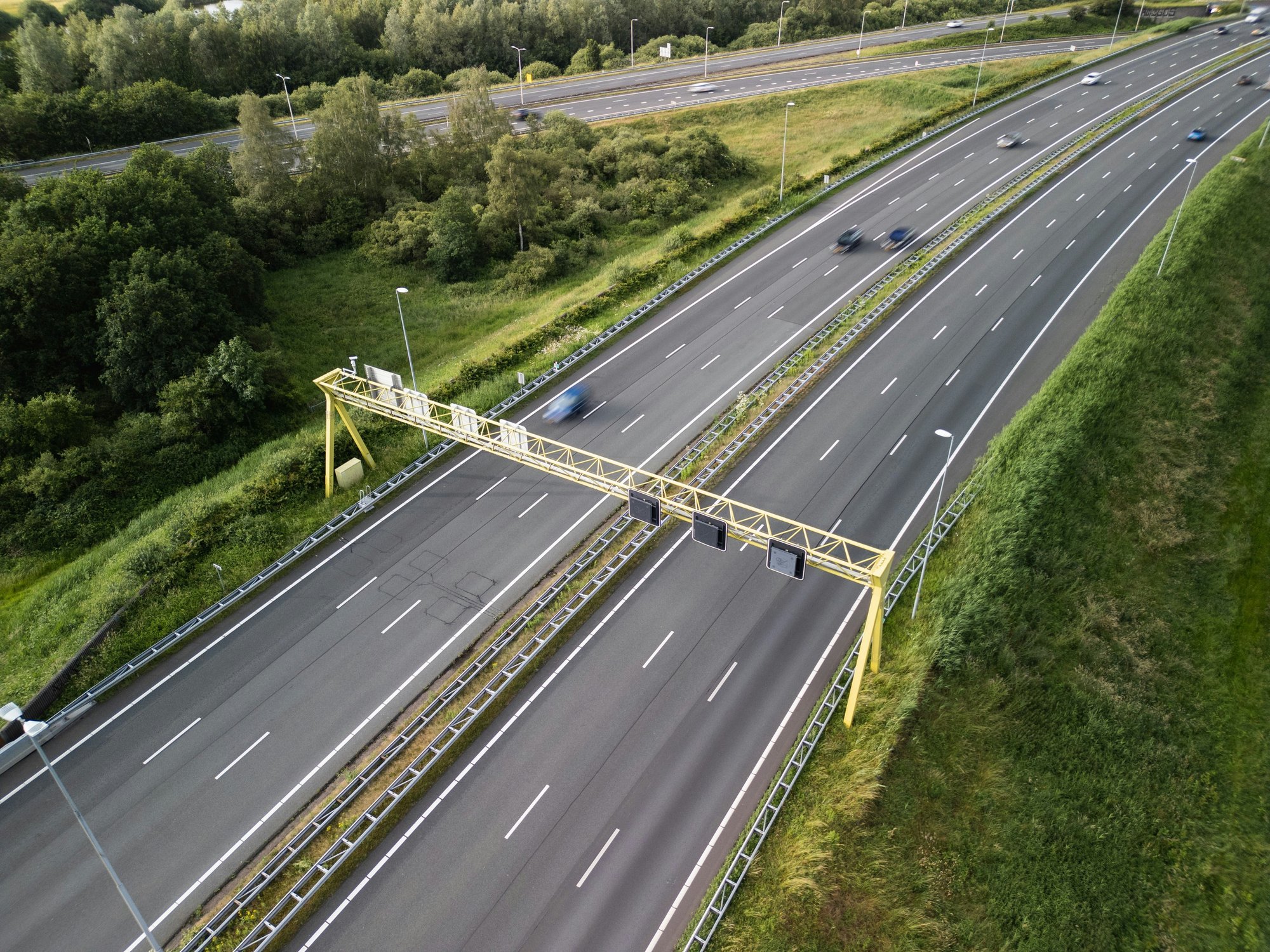 Luchtfoto van een Nederlandse snelweg met verkeersportaal, richting de stad