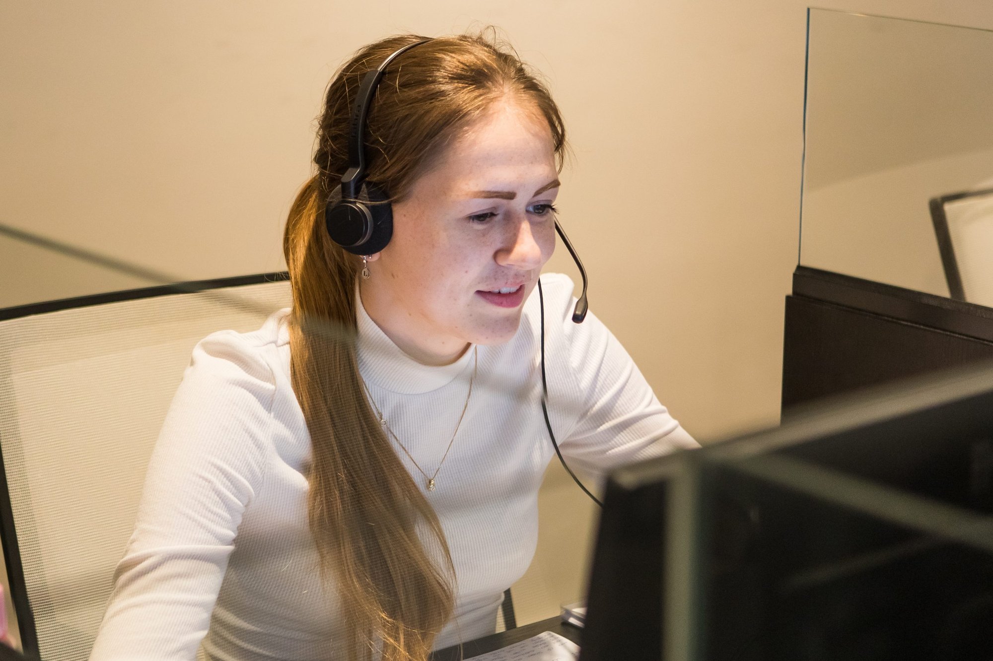 Accountmanager met headset achter monitoren, geconcentreerd in gesprek