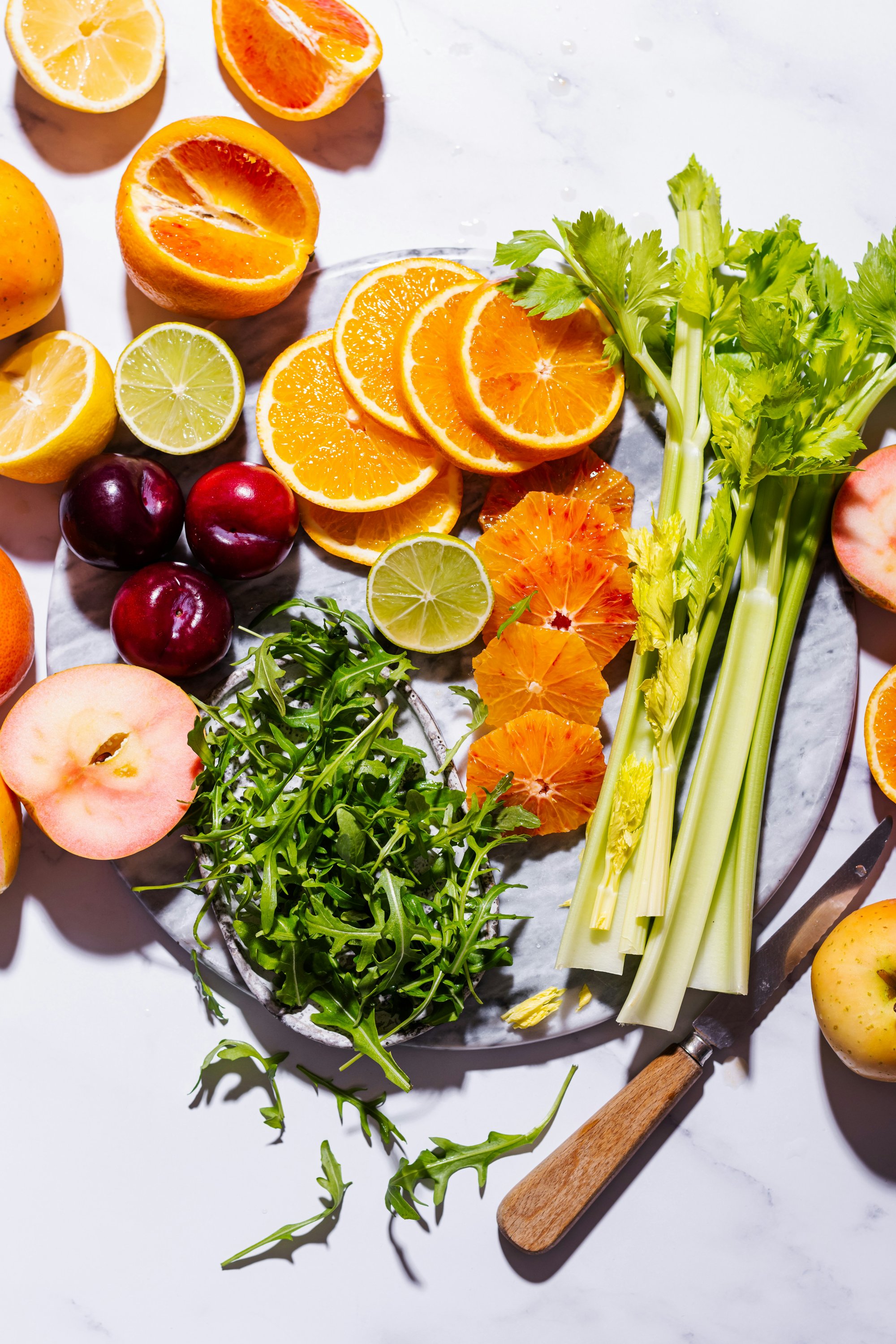 Verse groente en fruit uitgestald op een marmeren ondergrond — sinaasappels, kersen, appel, aardbei, selderij
