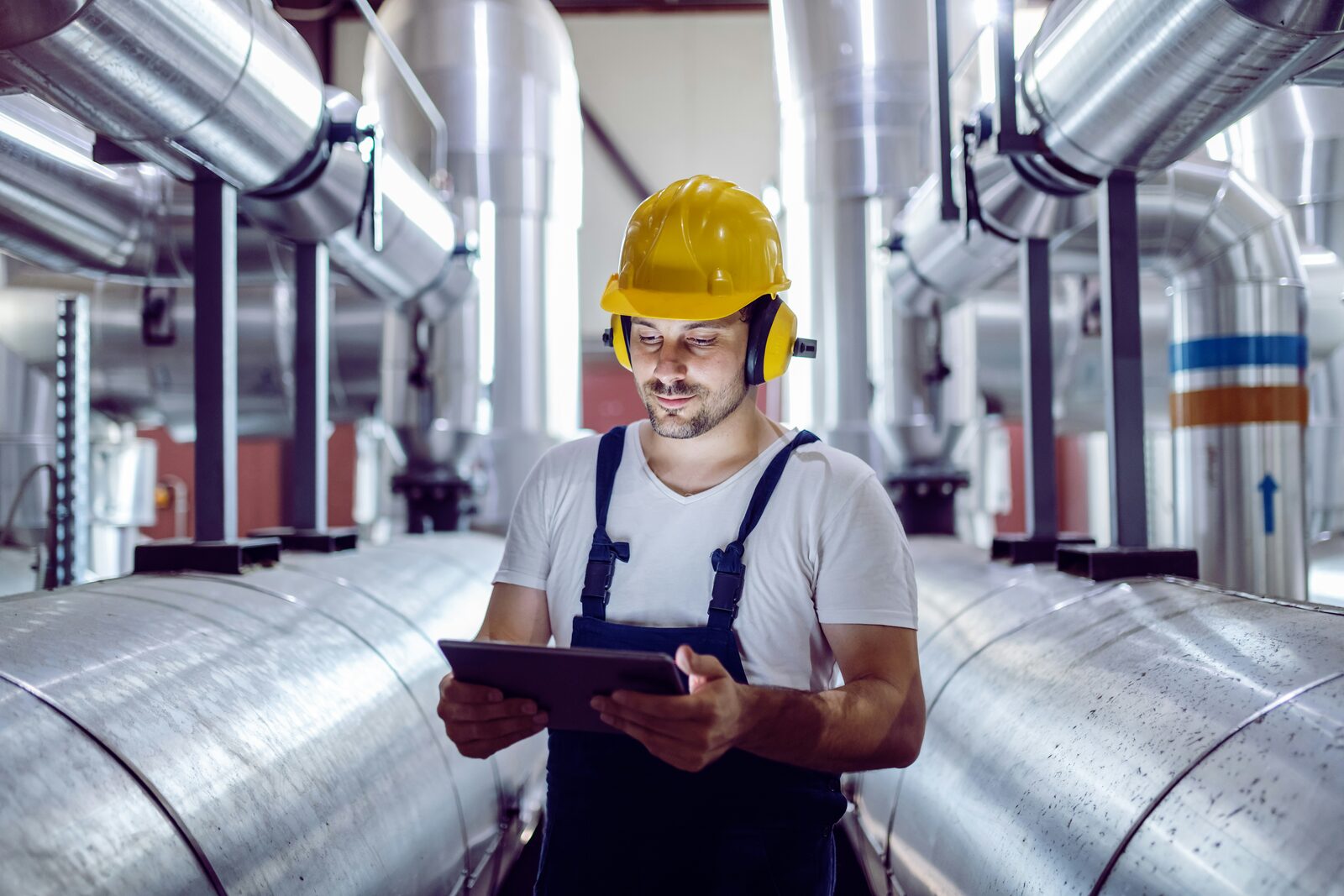 Engineer met tablet en helm in fabriek