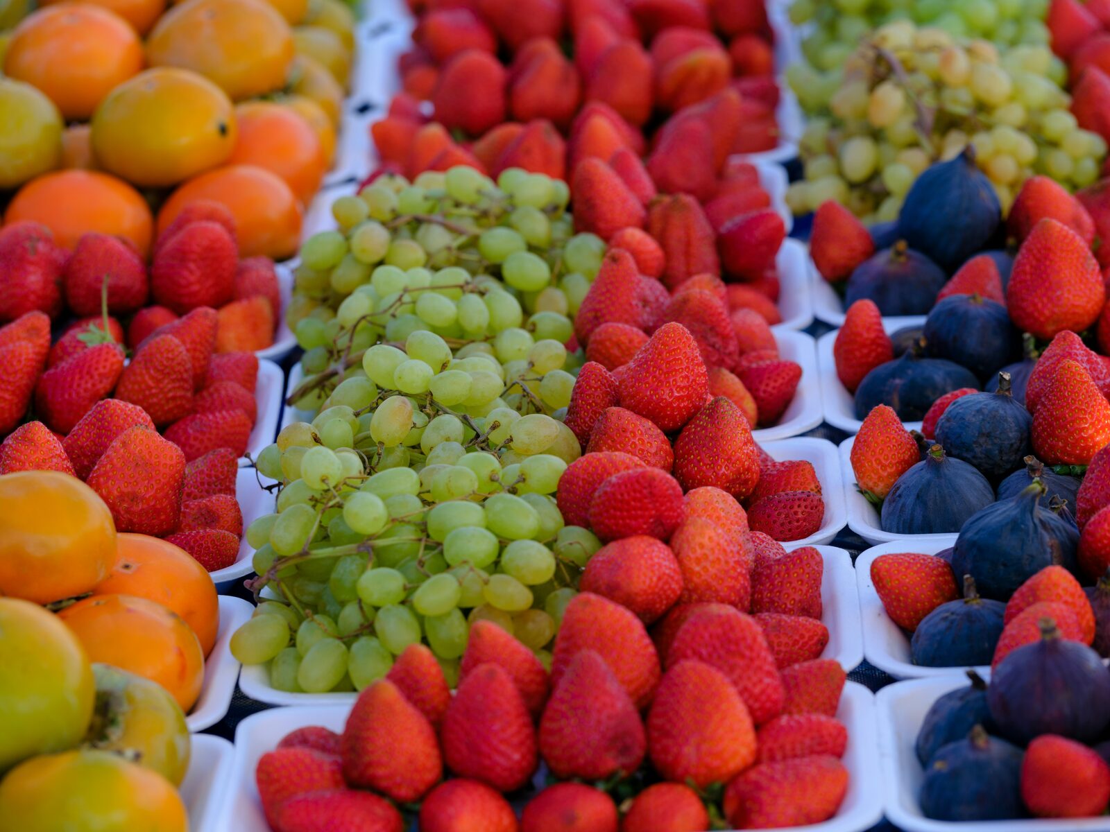 Verse vruchten op een marktstal — aardbeien, druiven, vijgen