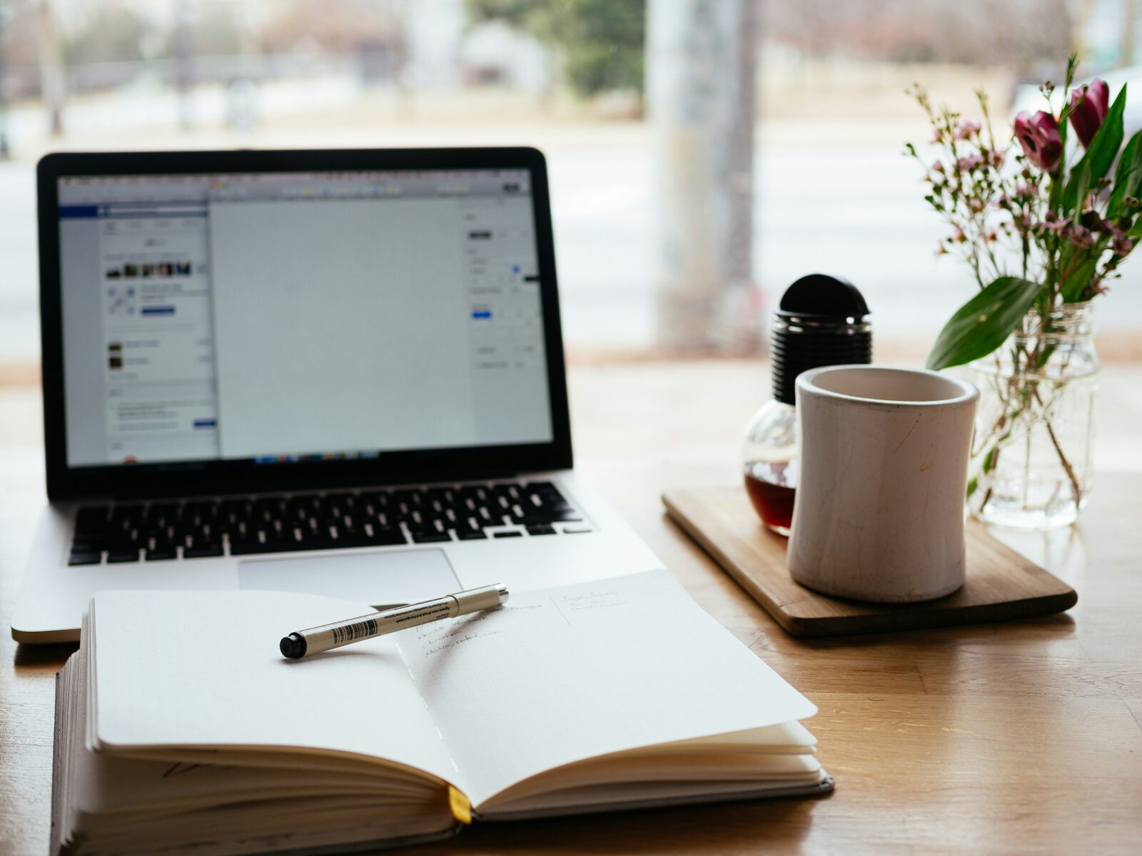 Werkplek met laptop, notitieboek en koffie