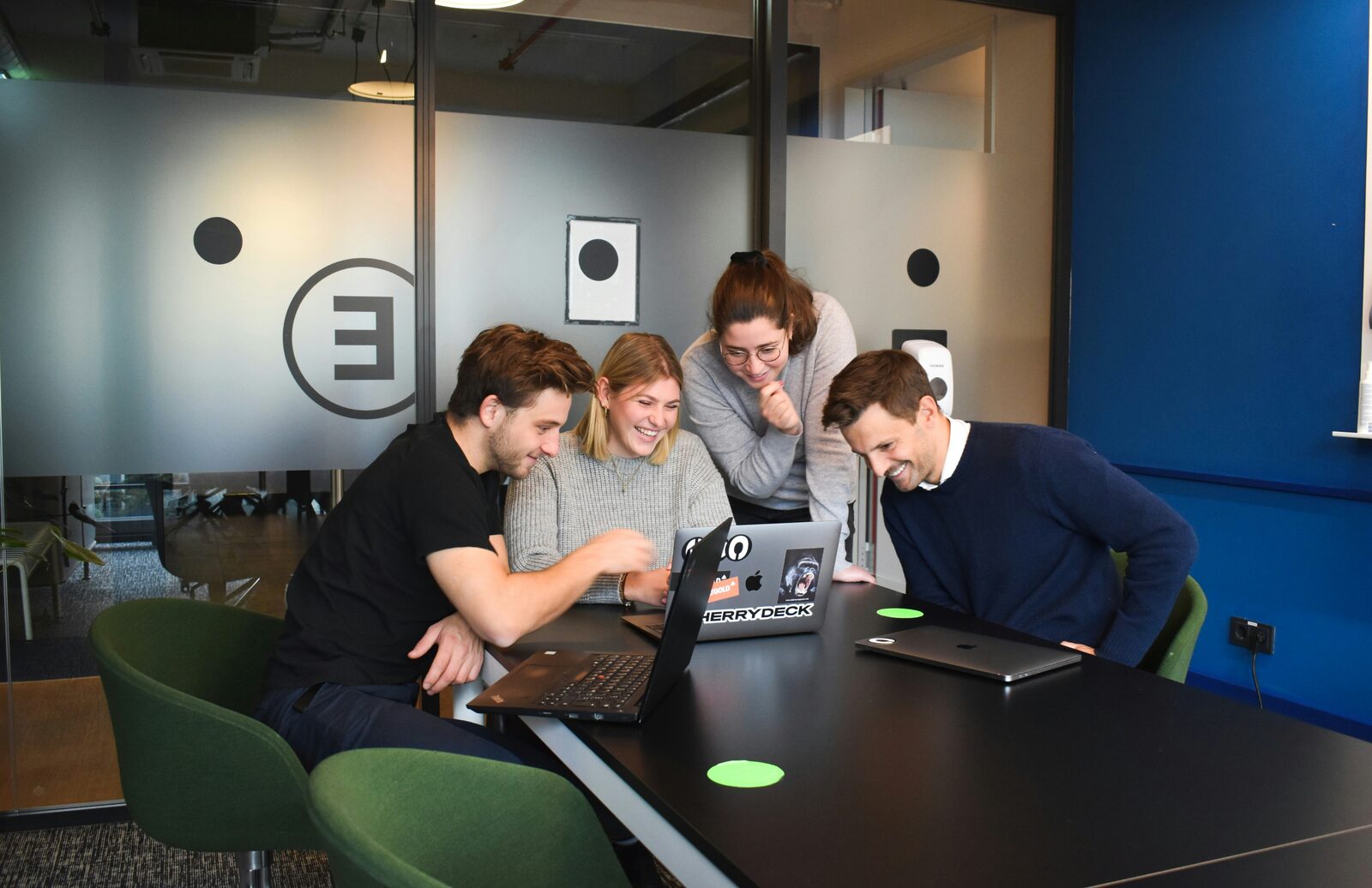Vier collega's geconcentreerd om een laptop heen