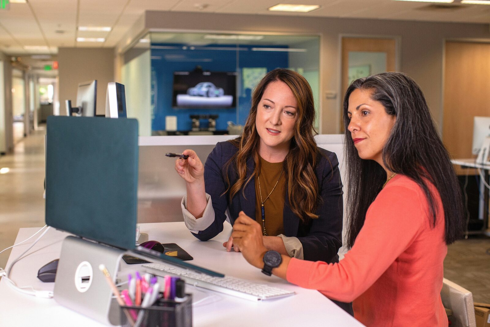 Twee collega's bespreken een vraagstuk achter laptop