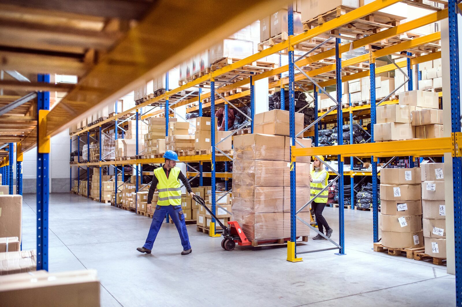 Magazijnmedewerkers met pompwagens in distributiecentrum